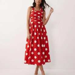robes à pois rouges dos nu mi-longue habillée lilah portée par une femme avec des sandales blanches et un col halter