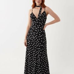 robes vintages rouges à pois noirs et blancs longue caraco encolure foulard portée par un mannequin femme rousse sur un fond blanc neutre
