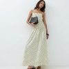 robes à pois jaune froncée la taille longue portée par un mannequin avec un sac noir et des sandales