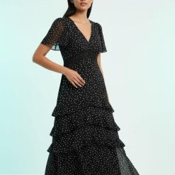 robes longues noires à pois étagés en mousseline volants avec col en v et manches courtes evasees portee par un mannequin