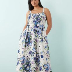 robes roses à pois blanc fines bretelles trapèze coupe corset imprimé fleuri bleu et violet portée par un mannequin sur fond bleu clair