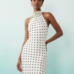pyjamas à pois ensemble en velours avec bords robe longue blanche a pois noirs col halter avec fleurs en relief portée par une femme
