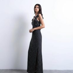 nuisettes à pois robe longue épaules volants noir portée par une femme aux cheveux bouclés avec une fente sur le côté