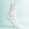 chaussettes à pois multi design crème et olive portées par une femme avec une tenue courte blanche sur fond blanc