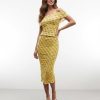 jupes courtes à pois jaune ensemble top épaules dénudées moulant froncé porté par une femme avec des sandales blanches