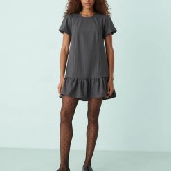 collants à pois floqués noir femme chic transparent portés par un mannequin avec une robe grise courte et des mocassins noirs