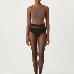 collants à pois transparents noir femme chic élégant mode portés par une femme debout sur un fond blanc neutre