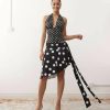 jupes courtes à pois noirs ensemble top décolleté plongeant asymétrique porté par un mannequin souriant avec des chaussures blanches