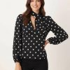 blouses à pois noirs et blancs avec détail foulard col en v manches longues portée par une femme