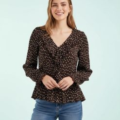 blouses à pois volantés détails blanc grain de café portée par une femme avec des manches longues et col en v
