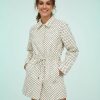 vestes à pois crème noirs boutonnée ensemble tissu technique col cordon serrage portée par une femme souriante à la taille cintrée avec poches