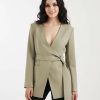 blazers à pois olive encolure ronde avec lin mélangé croisé porté par une femme avec ceinture nouée