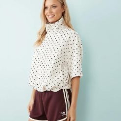 vestes à pois crème col courte et montant manches courtes style rétro élastique en bas portée par une femme sur fond bleu clair