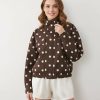 vestes à pois boutons technique marron et crème fermeture bascule portée par une femme avec un col montant et des poches plaquées sur le devant