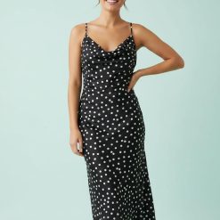 robes moulantes à pois monochrome encolure dégagée longueur mollet coupée biais robe satinée noire à pois blancs avec bretelles fines portée par une femme