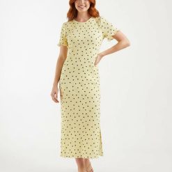 robes moulantes à pois jersey texturé longue en vanille française portée par un mannequin aux cheveux roux avec des manches courtes