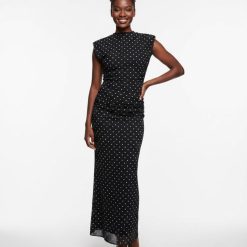 robes moulantes à pois noir col montant longue épaulettes portée par une femme avec des escarpins noirs sur fond blanc