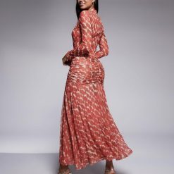 robes à pois rouge tulle imprimé manches longues lea portée par un mannequin vue de dos avec des fronces à la taille et des talons haut argentés