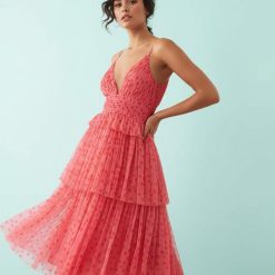 robes longues rouges à pois blancs rose caraco tulle décolleté plongeant volants portée par une femme sur fond bleu clair avec jupe à étages et fines bretelles