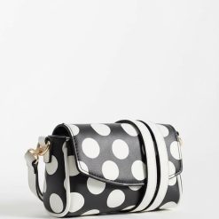 sacs à main à pois réglable bandoulière mini monochrome en cuir noir et blanc porté par une femme en blazer noir élégante