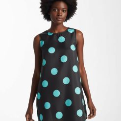 sacs de voyage à pois épaule porté marron foncé robe courte noire sans manches imprimée de grands pois bleu turquoise portée par une femme