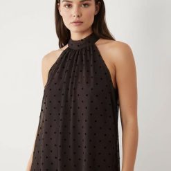 robes asymétriques à pois marron en tricot dos nu portée par un mannequin aux cheveux bruns et col montant sans manches