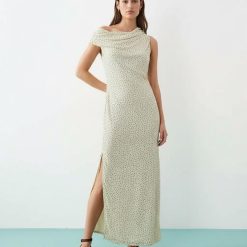 robes asymétriques à pois crème avec tombante épaule mollet longueur et fente latérale portée par un mannequin avec des sandales marron