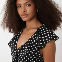 robes à pois noirs et blancs noir volants portée par un mannequin aux cheveux bouclés