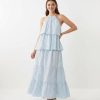robes bleu ciel à pois volumineuse longue étagés volants portée par une femme sur un fond blanc neutre