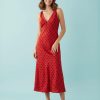 nuisettes à pois robe col v mi longue et rouge portée par un mannequin sur un fond bleu clair