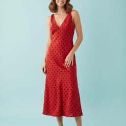 nuisettes à pois robe col v mi longue et rouge portée par un mannequin sur un fond bleu clair