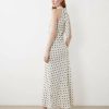nuisettes à pois crème robe satin encolure licou détails fleurs portée par une femme vue de profil avec des talons noirs sur fond blanc