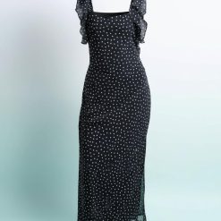 nuisettes à pois robe longue épaules volants noir portée par une mannequin aux cheveux crépus sur fond bleu pastel