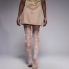 collants à pois blancs transparents motif fantaisie femme portés par un mannequin vue de dos portant une robe courte beige