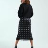 jupes courtes à pois satin dentelle bordée motif noir petite portee par un mannequin vue de dos avec des talons hauts noirs