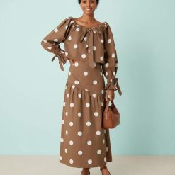 blouses à pois ample encolure ronde nœuds marrons blancs portée par une femme avec une jupe assortie et des chaussures marron