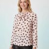 blouses à pois roses encolure dégagée avec nœud manches longues couleur rose et marron portée par mannequin blond avec pantalon en cuir noir