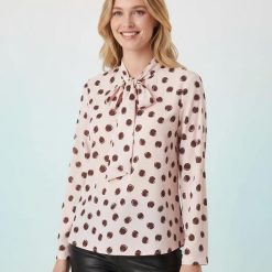 blouses à pois roses encolure dégagée avec nœud manches longues couleur rose et marron portée par mannequin blond avec pantalon en cuir noir