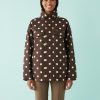 vestes à pois boutons technique marron et crème fermeture bascule portée par une mannequin sur un fond bleu clair avec un col montant