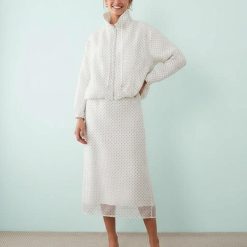 vestes à pois ensemble jupe et veste ivoire porté par une femme avec un col montant zippé et une jupe midi assortie