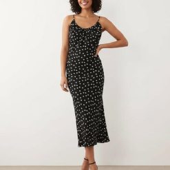 robes moulantes à pois monochrome encolure dégagée longueur mollet coupée biais portée par une femme souriante avec des sandales noires à talons