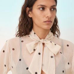blouses à pois mousseline froissé foulard encolure manches ange effet transparent beige portée par une femme avec un jean noir