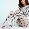 collants à pois motif cœurs rayés et noir portés par une femme souriante assise sur un fond blanc avec un haut assorti