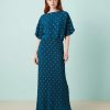 robes asymétriques à pois bleu sarcelle dénudées plissée longue métallisé épaules portée par un mannequin aux cheveux roux avec des sandales dorées