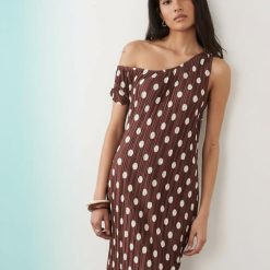 robes asymétriques à pois dénudées épaules plissée et multicolore robe marron à pois blancs plissée asymétrique portée par une femme jeune et élégante posant contre un mur clair
