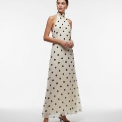 robes mousseline à pois col montant longue dos nu couleur crème avec des motifs de pois noirs portée par un mannequin