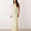 nuisettes à pois longue dentelle robe fines bretelles avec bordures imprimé jaune claire portée par une femme sur fond bleu