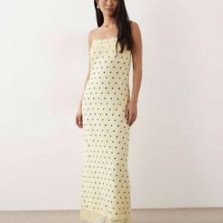 nuisettes à pois longue dentelle robe fines bretelles avec bordures imprimé jaune claire portée par une femme sur fond bleu