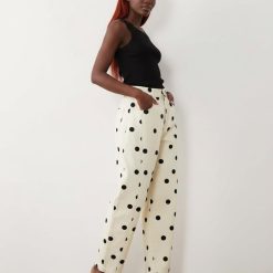 jeans à pois crème bouffant design pantalon coupe large imprimé avec des motifs ronds noirs porté par une femme avec un débardeur noir