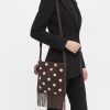 sacs de voyage à pois ornementé épaule porté marron avec franges et perles blanches porté par une femme en costume noir